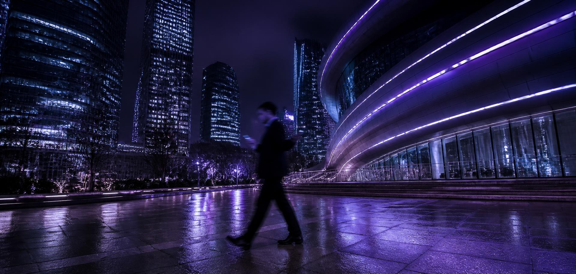 Founder walking through a city plaza at night